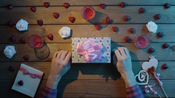 Adult man puts valentine onto present box, top view — Stock Video