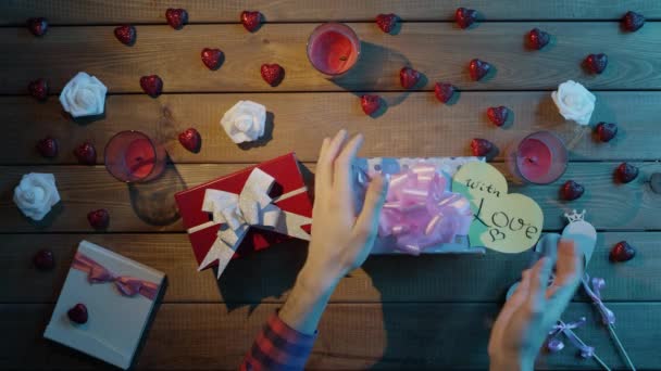 Glücklicher Mann versucht zu verstehen, was in seinen Weihnachtsgeschenken steckt und schüttelt sie, Draufsicht — Stockvideo