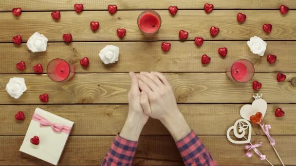 Man with paper heart sits by wooden table, top view — Stock Video