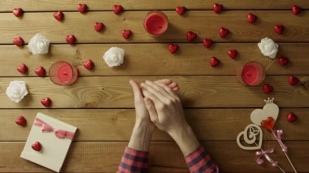 Joven con el corazón de papel se sienta junto a la mesa de madera, vista superior — Vídeo de stock