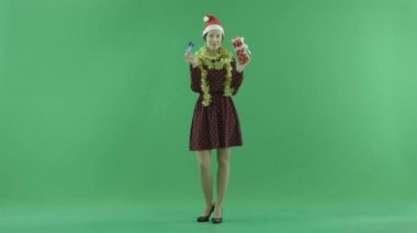 Genç bir kadın Noel hediyesi yeşil ekran üzerinde satın almak için bir kredi kartı izleyiciye gösteriyor