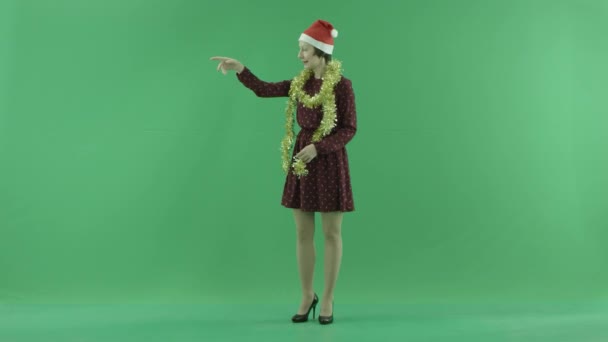 Молода жінка Різдво закликає до кого-то з лівого боку зелений екран — стокове відео
