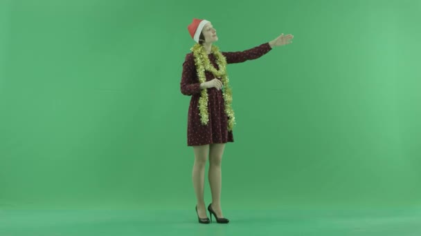 Молода жінка Різдво закликає до кого-то з правого боку зелений екран — стокове відео