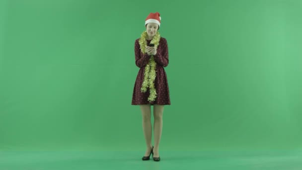 Een jonge vrouw van de kerst is het schrijven van iets met haar telefoon op het groene scherm — Stockvideo