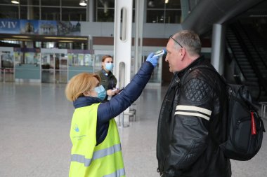 Havaalanı çalışanları ve sınır muhafızları Ukrayna 'nın Lviv kentindeki Danylo Halytskyi Uluslararası Havalimanı' na gelen yolcuların vücut sıcaklıklarını kontrol ediyorlar. SARS-CoV-2 koronavirüsünden kaynaklanan COVID-19 hastalığı