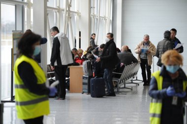 Havaalanı çalışanları ve sınır muhafızları Ukrayna 'nın Lviv kentindeki Danylo Halytskyi Uluslararası Havalimanı' na gelen yolcuların vücut sıcaklıklarını kontrol ediyorlar. SARS-CoV-2 koronavirüsünden kaynaklanan COVID-19 hastalığı