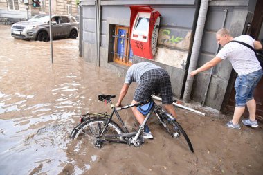 Lviv, Ukrayna, 17 Ağustos 2018. Ukrayna 'nın batısındaki Lviv şehrinde meydana gelen şiddetli fırtınanın ardından insanlar sel sularında yürüyorlar.. 
