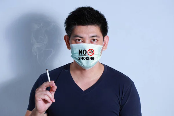 Stop smoking concept young man smoking cigarette with  protective mask