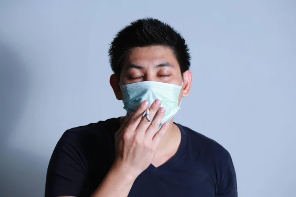 Stop smoking concept young man smoking cigarette with  protective mask