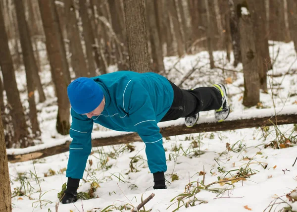 Man performs exercise in the winter woods. — Stock Photo, Image