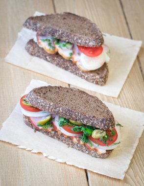 Çuval bezi bir parçası ile ahşap bir masa üzerinde taze sandviç.