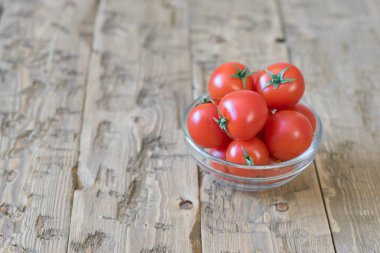 Rustik bir masada cam bir kase kiraz domates.