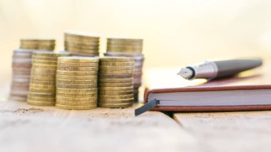 Bir defter ve rustik bir tabloda dolma kalem ile metal paraları.