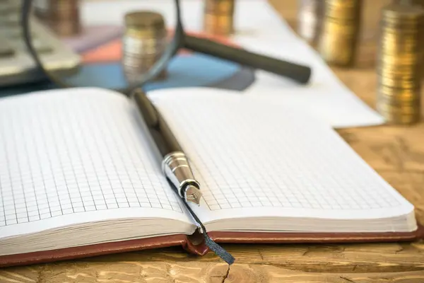 Stylo plume, calculatrice, pièces et cahier sur une table en bois . — Photo