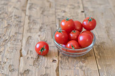 Rustik bir masada cam bir kase kiraz domates.