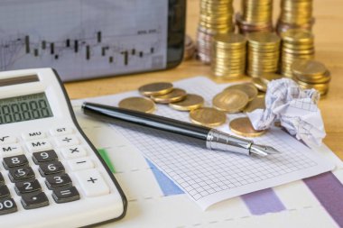 Metal paralar ve rustik bir tablo hesap makinesi.