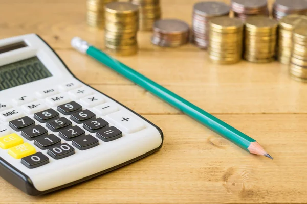 Monedas de metal y calculadora sobre una mesa rústica . — Foto de Stock