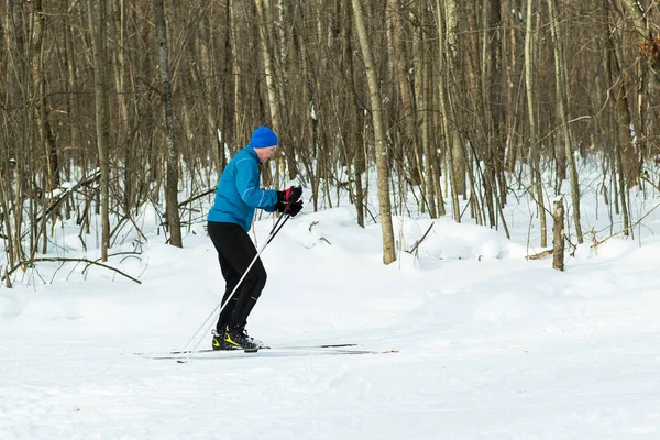 青いスーツを着た男がスキーで冬の森で実行します。. — ストック写真