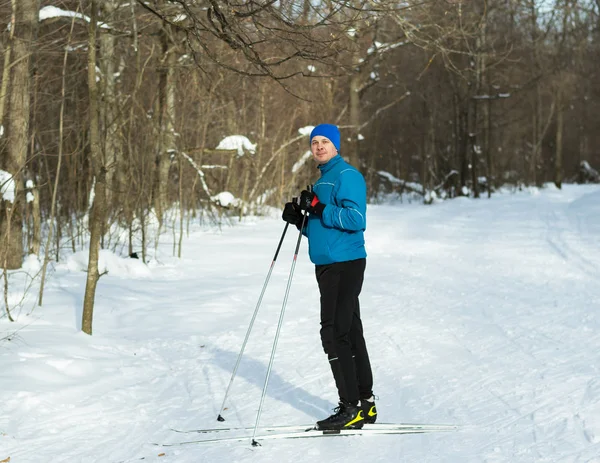 青いスーツを着た男がスキーで冬の森で実行します。. — ストック写真