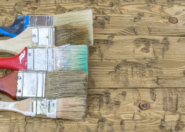Un conjunto de viejos pinceles multicolores sobre una mesa de madera . — Foto de Stock