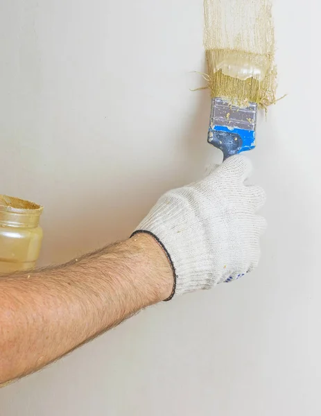 La main d'un homme dessine une ligne verticale de peinture sur le mur . — Photo