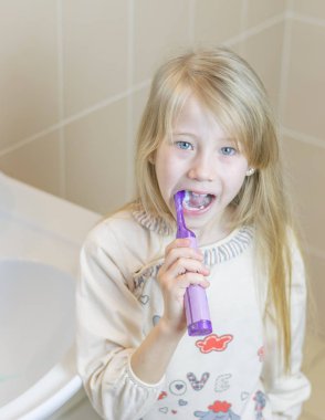 Onun diş elektrikli diş fırçası ağzını açık ile fırçalama kız.