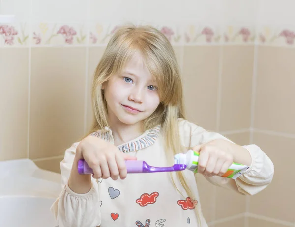 Schönes Mädchen bekommt Zahnpasta auf einer elektrischen Zahnbürste. — Stockfoto