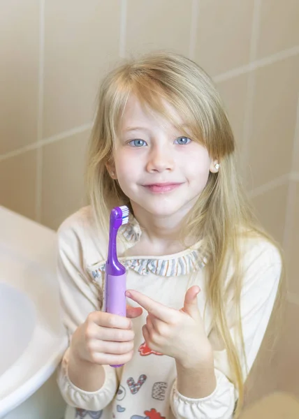A lány azt mutatja, hogy az élvezetek az elektromos fogkefe. — Stock Fotó