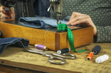 Eski bir dikiş makinesi üzerinde çalışan kadın.