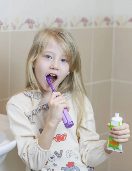 Lány nyitott cső az elektromos fogkefe és fogkrém. — Stock Fotó