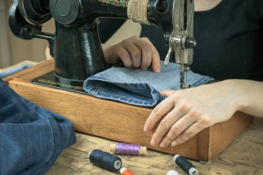 Bir kadın bir eski dikiş makinesi üzerinde çalışıyor.