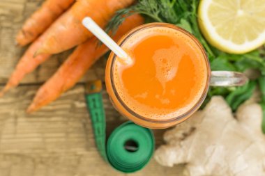 Zencefil kökü ve rustik ahşap masa üzerinde ölçüm bandı ile havuç güler yüzlü.