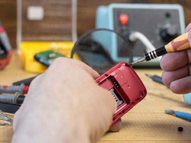 Bir adam bir cep telefonu tamir için inceliyor.