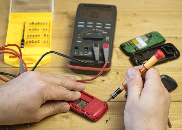 Een man reparaties rode mobiele telefoon. — Stockfoto