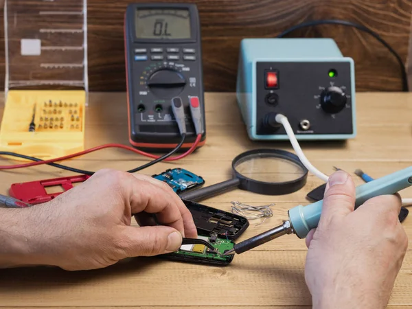 Man reparatie mobiele telefoon met een soldeerbout. — Stockfoto