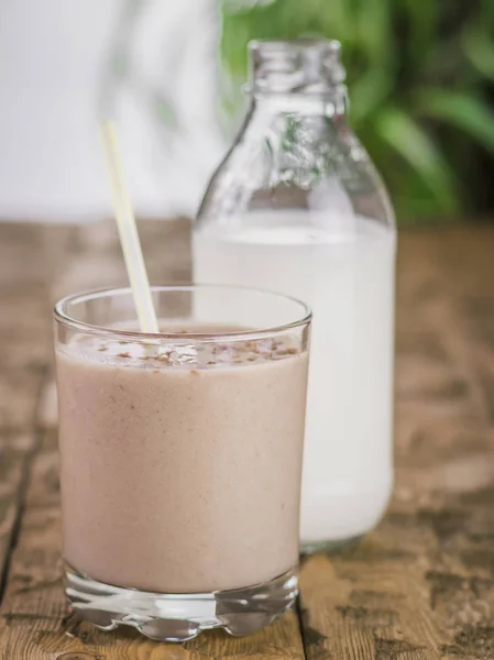 Botol dengan susu dan coklat smoothie dengan pisang dan pir di atas meja kayu . — Stok Foto