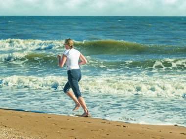 Kadın çıplak ayak ile sahilde koşu.