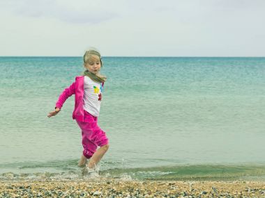 Güzel kız eğleniyor soğuk denizde oynarken.