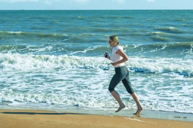 Jogging sahilde fırtınalı bir denizde çerçevede bir kadındır.