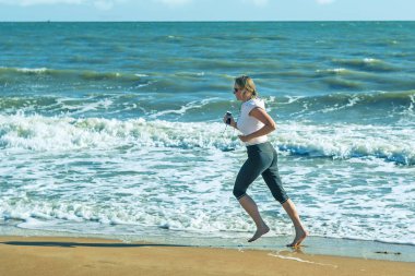 Jogging sahilde fırtınalı bir denizde çerçevede bir kadındır.