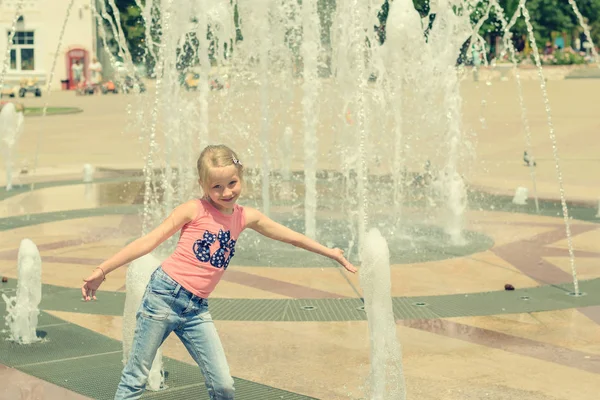 Little girl playing with water in city fountain. — Stock Photo, Image