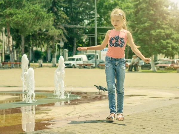 Hermosa niña camina cerca de la fuente de la ciudad . — Foto de Stock