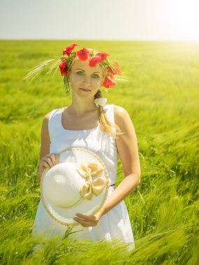 Güneşin haşhaş kafasında çelenk ile beyaz elbiseli bir kadın.