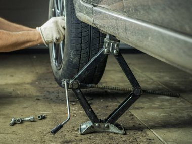 Arabanın arka tekerlek onarılması eldivenli bir adam.