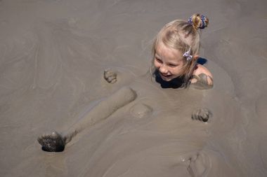 Deniz kıyısında bir çamur volkan küçük kız banyoları.