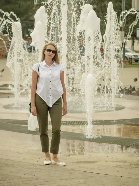 Retrato de una hermosa mujer en pleno crecimiento en la fuente de la ciudad . — Foto de Stock