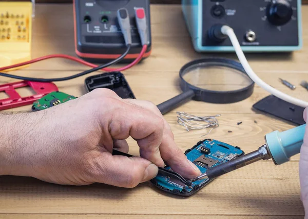 Hombre reparando un circuito defectuoso Junta de un teléfono móvil . — Foto de Stock