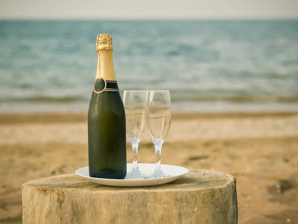 Een fles koude champagneglazen en aardbeien op een zandstrand. — Stockfoto