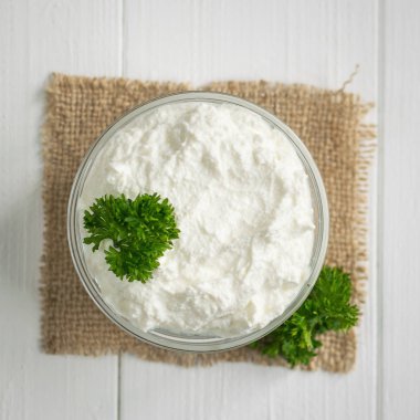 Taze ahşap bir masa üzerinde bir cam kasede peynir maydanoz ile yapılmış.