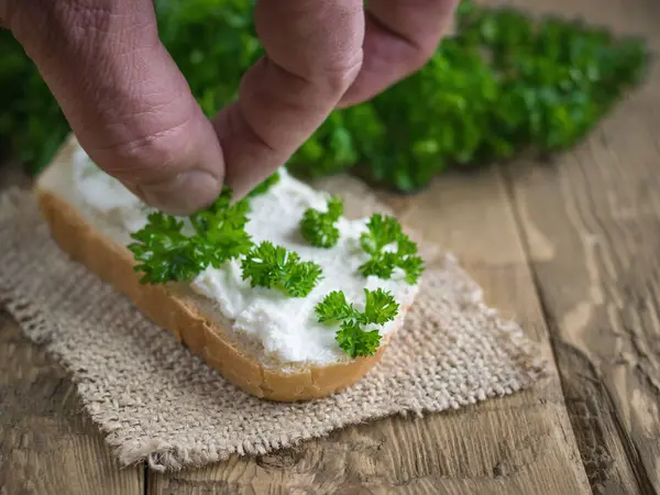 Männer-Hand dekoriert frisch gebackenes Brot mit Quark-Creme. — Stockfoto